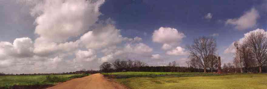 McDavid:-Abandoned-Farm_01.jpg:  country road, dirt road, red clay road, windmill, chimney, cumulus clouds, fields, farmer