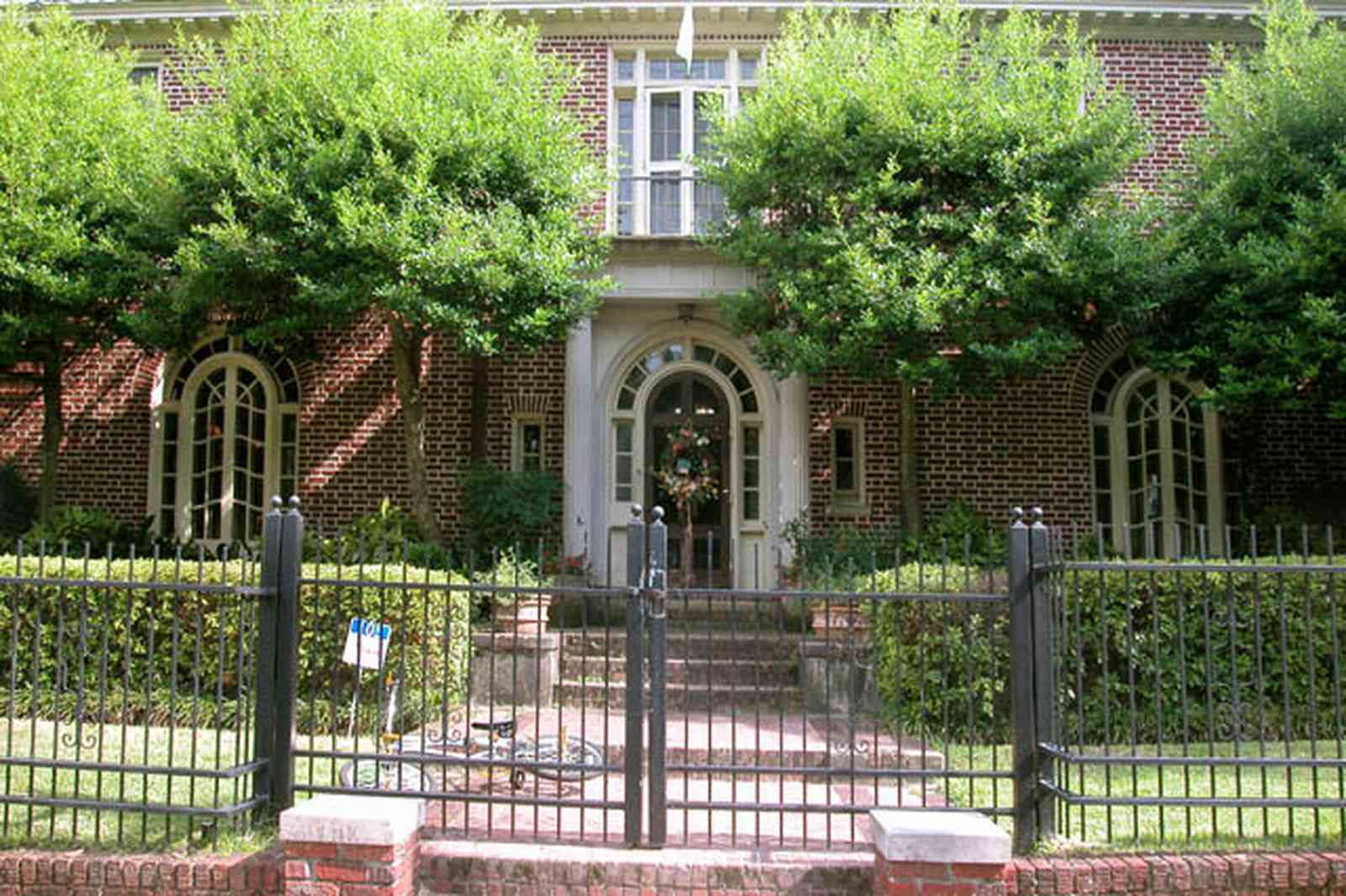 North-Hill:-105-West-Gonzales-Street_02.jpg:  red brick house, fireplace, sidewalk, wrought iron fence, green tile roof