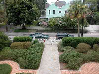 North-Hill:-304-West-Gadsden-Street_31.jpg:  formal garden, brick sidewalk, picket fence, victorian house, magnolia tree, crepe myrtle trees, palm tree, north hill preservation district