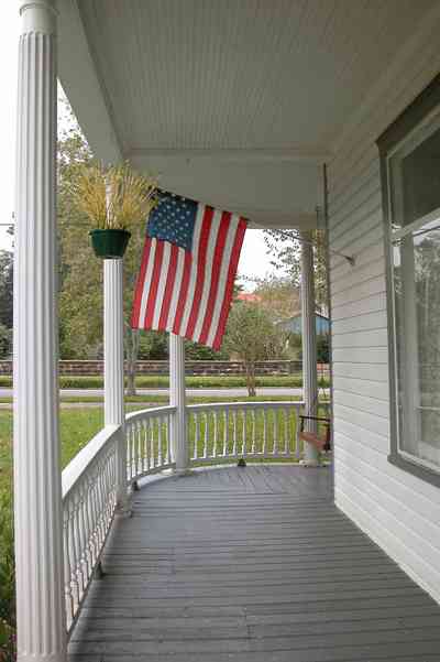 North-Hill:-52-West-Gonzalez-Street_04.jpg:  victorian front porch, queen anne style, american flag, curved railing