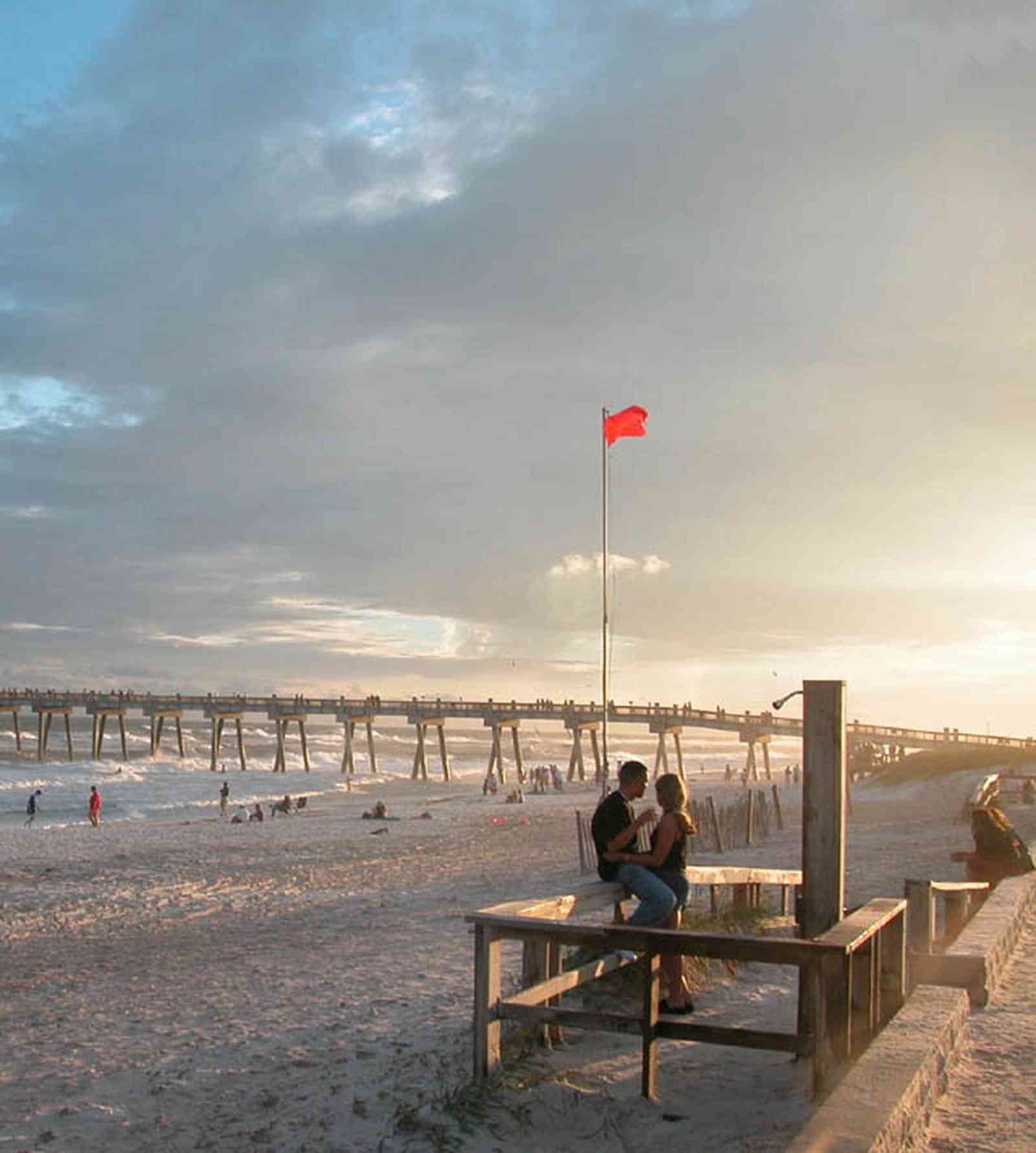 Pensacola-Beach:-Sunset_02a.jpg:  warning flag, surf, surfer, beach, sand, sunset, fishing pier, gulf of mexico