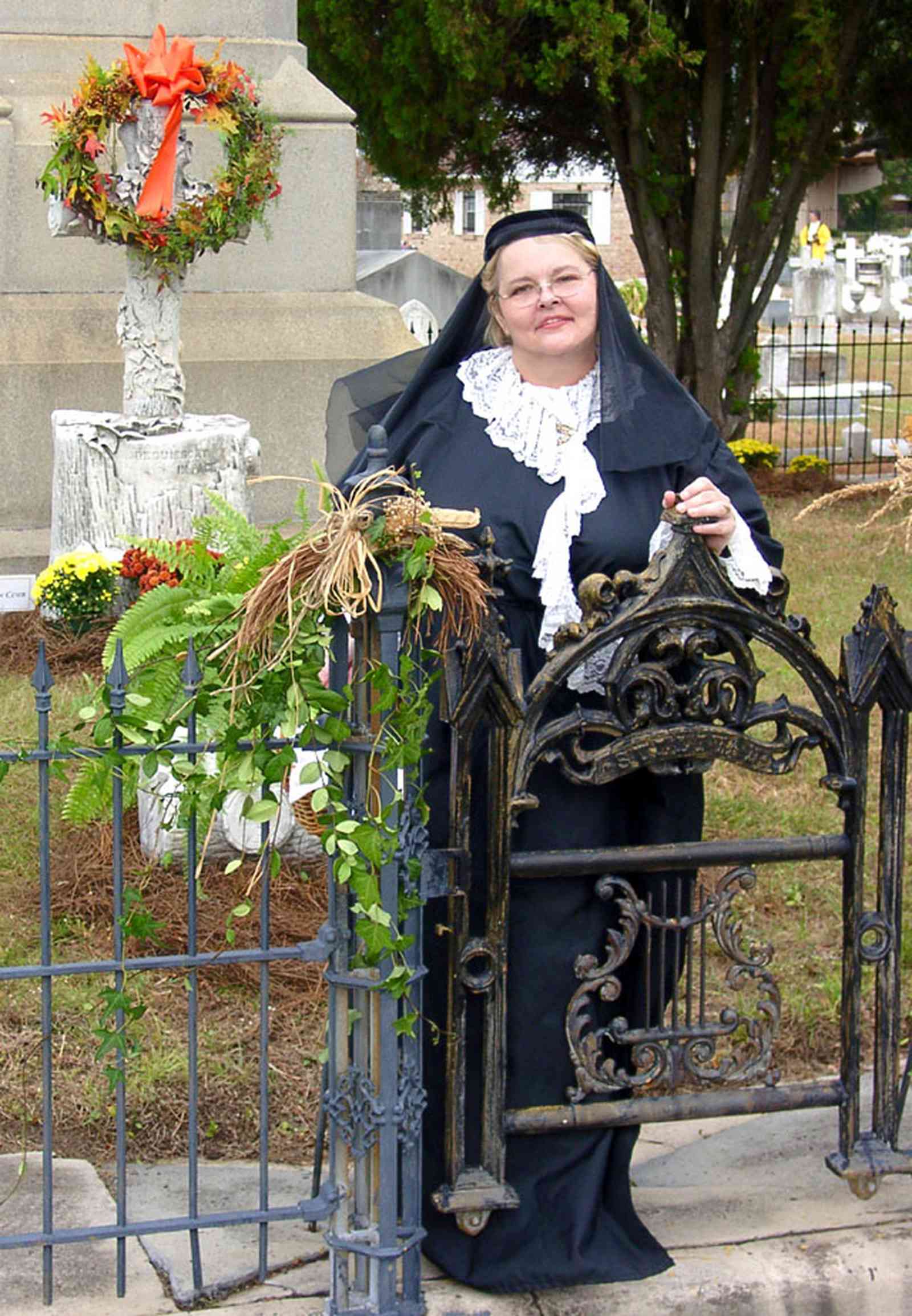 Pensacola:-Seville-Historic-District:-St-Michael-Cemetery_26.jpg:  wrought iron fence, wrought iron gate, floral wreath, mourner, cross, monument