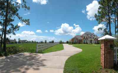 Cantonment:-Milestone:-Red-Brick-Mansion-A_00a.jpg:  circular driveway, gate, entrance, white board fence, red brick, pine tree, dormer windows, country road, subdivision