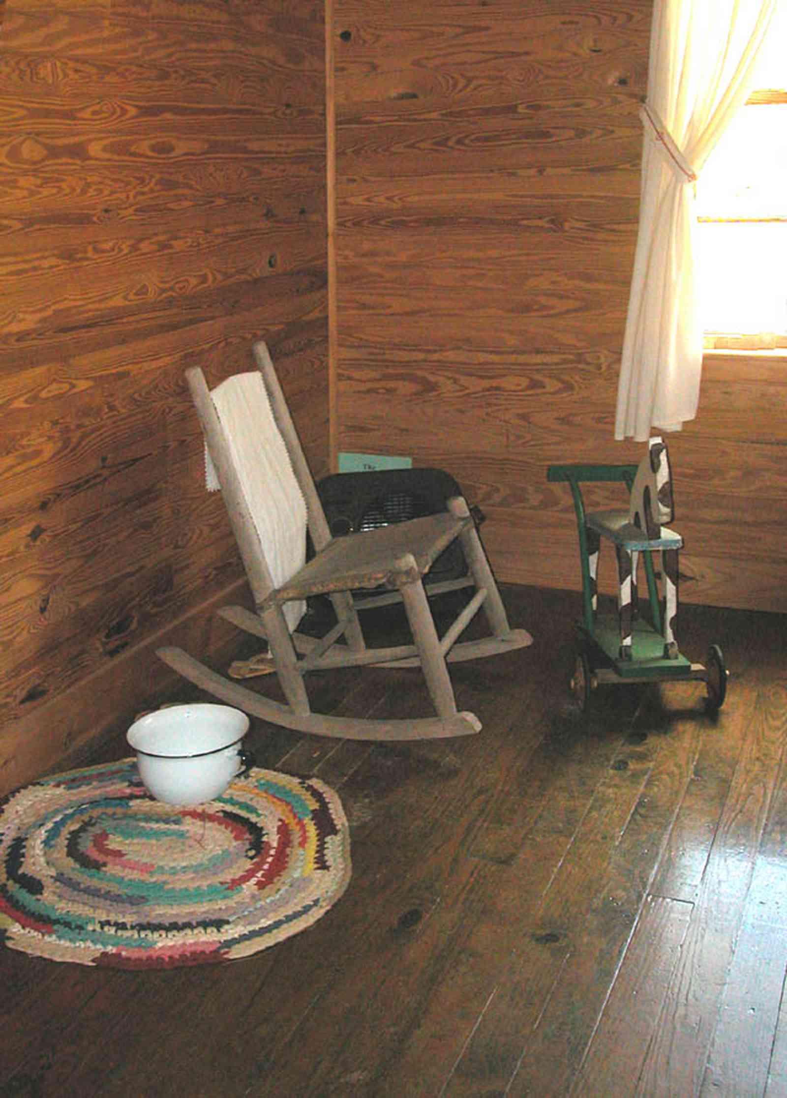 Cantonment:-Roy-Hyatt-Environmental-Center-Dog-Trot-House_11.jpg:  iron bed, quilt, ragdoll, bedroom, wooden walls, wood floor, slop pot, rocking chair
