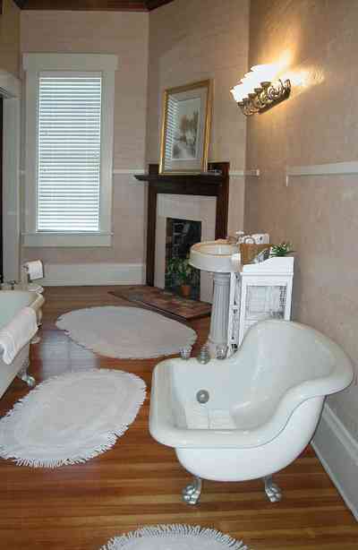 Century:-Tannenheim_01n.jpg:  bathtub, fireplace, pedestal sink, wainscotting, wooden floors, ventian blinds, fringed rugs