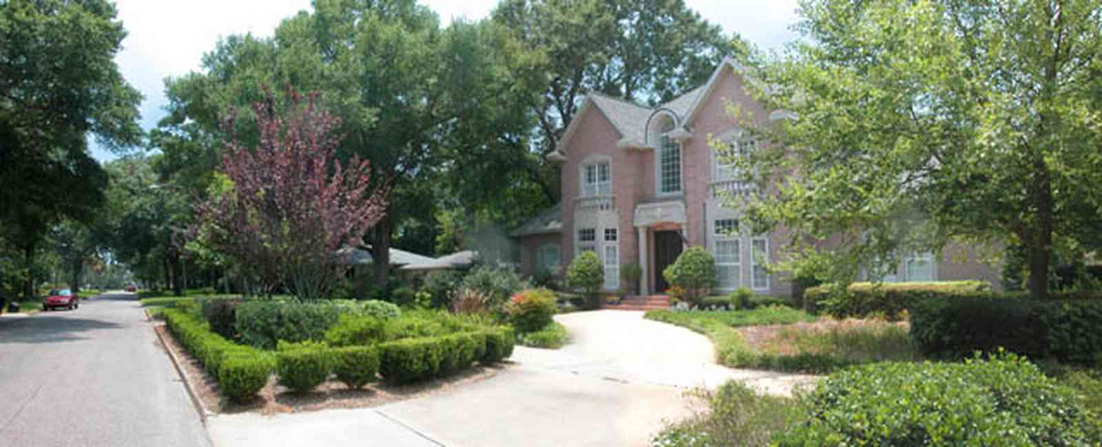 East-Hill:-617-19th-Avenue_07.jpg:  boxwood hedge, pink brick house, circular driveway, oak trees, river birch tree