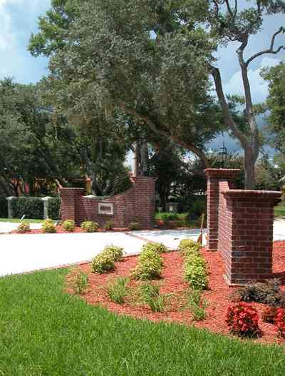 Gulf-Breeze:-706-Fair-Point-Drive_00.jpg:  gate, entrance, formal driveway, lanterns, oak trees, brick columns