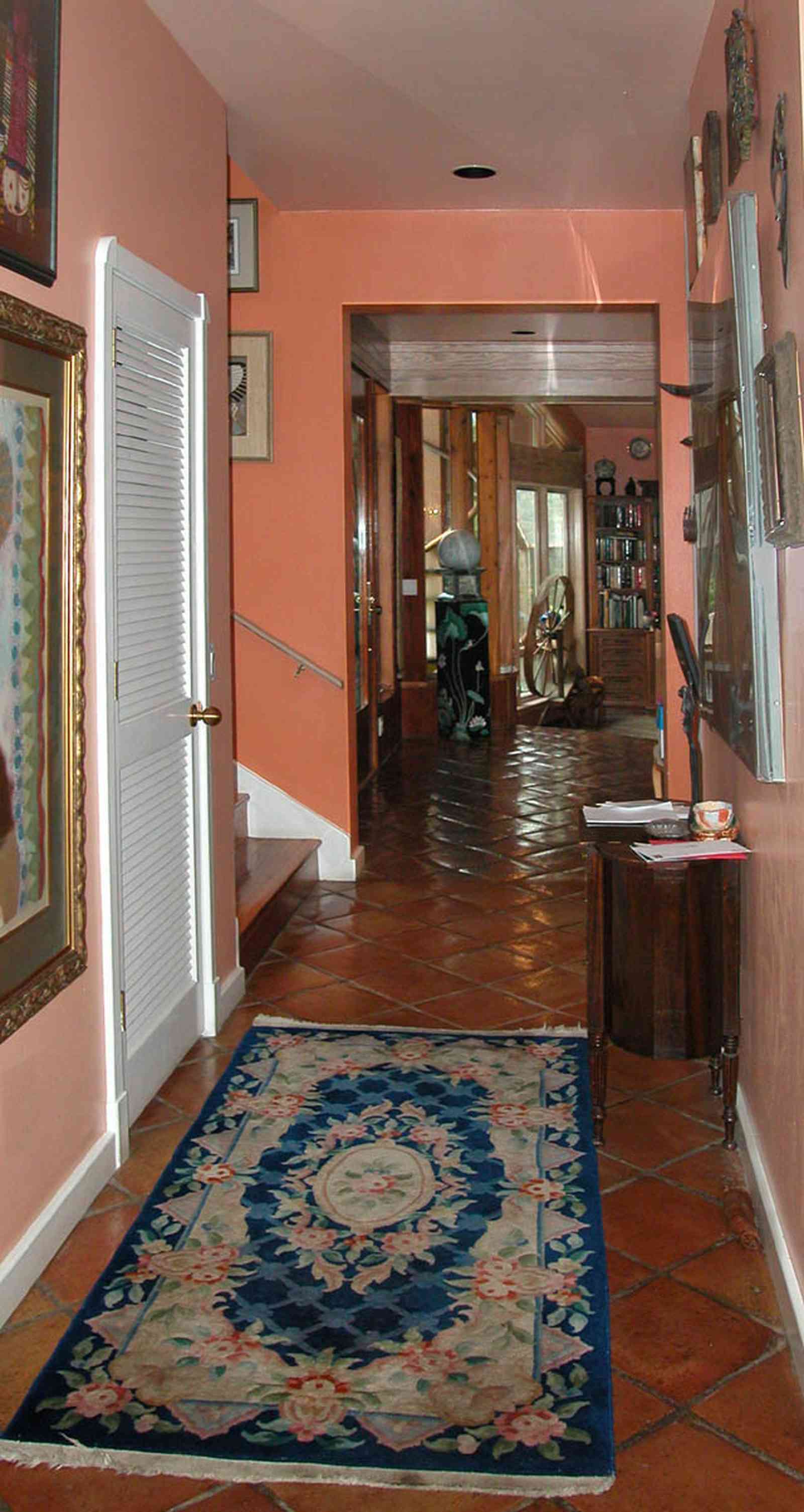 Gulf-Breeze:-92-High-Point-Drive_09.jpg:  hallway, stairs, credenza, oriental rug, spinning wheel, mexican tile floor