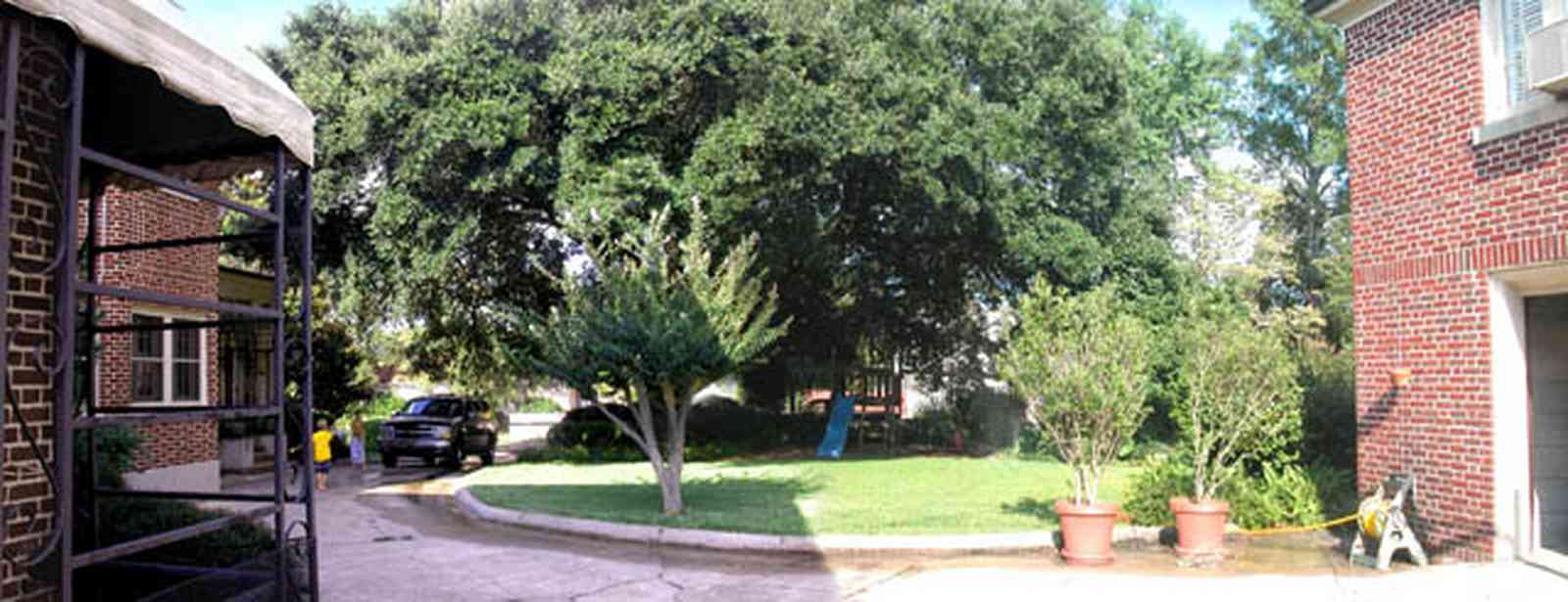 North-Hill:-105-West-Gonzales-Street_20.jpg:  driveway, red brick house, garage door, mud room, crepe myrtle tree, oak tree