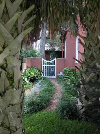 North-Hill:-123-West-Lloyd-Street_02.jpg:  palm trees, gate, garden, gravel path, stucco house, walled garden, north hill preservation district