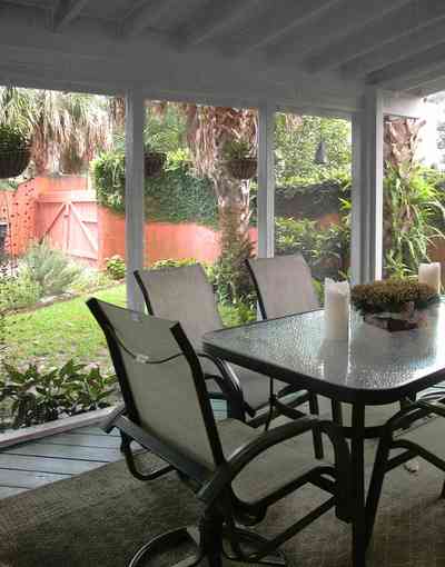 North-Hill:-123-West-Lloyd-Street_25.jpg:  screened porch, stucco walls, vine covered wall, garden gate, garden, backyard, palm trees, glass-top table