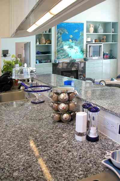 Pensacola-Beach:-Ariola-Drive-Art-Deco-House_27.jpg:  granite countertop, salt and pepper shaker, spice rack, kitchen sink, open floor plan, cake plate, fireplace, marble, wooden floor