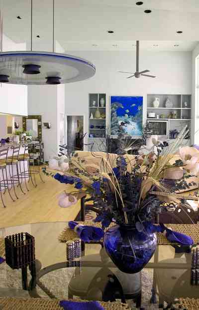 Pensacola-Beach:-Ariola-Drive-Art-Deco-House_29.jpg:  flower arrangement, glass table, open floor arrangement, bar stools, kitchen counter, wooden floors, beach front home