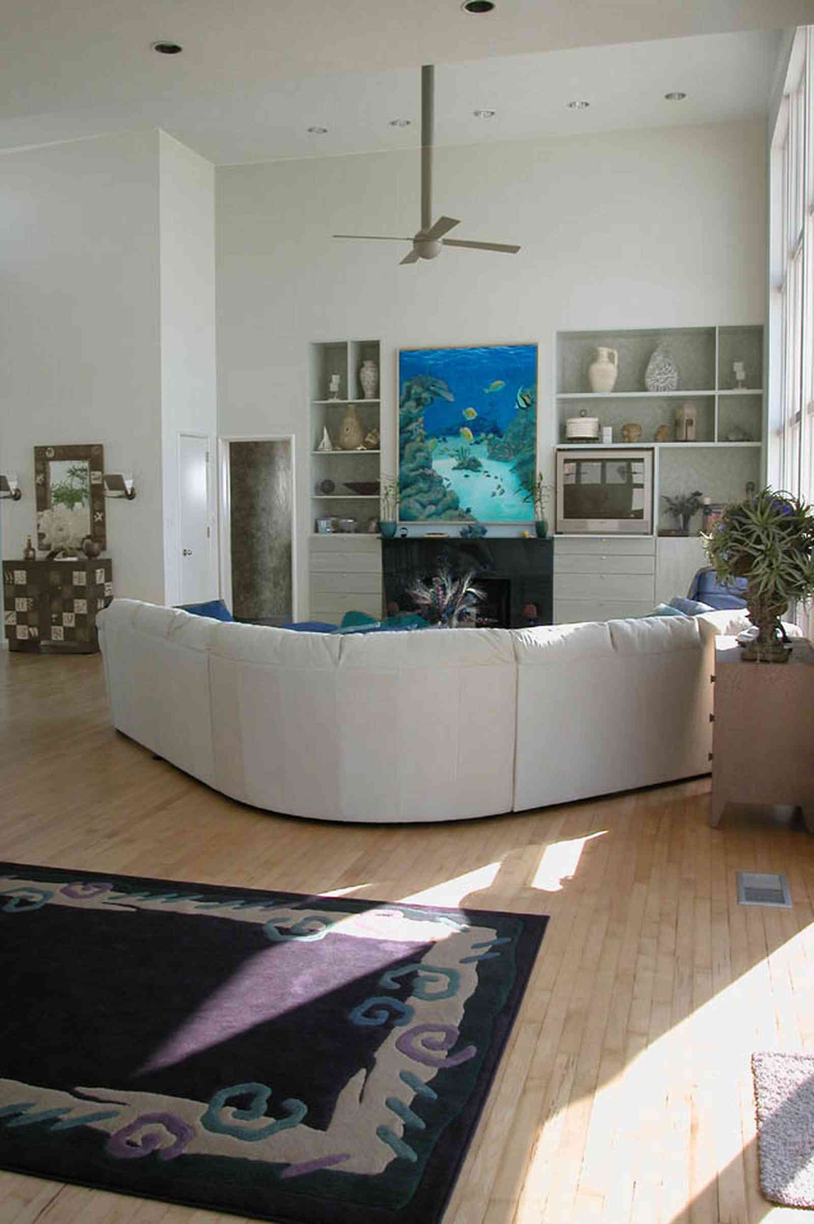 Pensacola-Beach:-Ariola-Drive-Art-Deco-House_29a.jpg:  beach house, marble mantle, fireplace, waterfront property, ceiling fan, sectional leather sofa, area rug, shelves, wood floors, beach front property