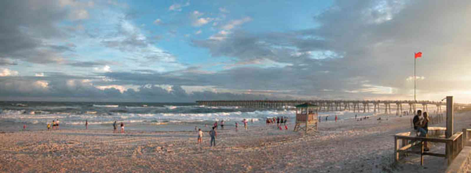 Pensacola-Beach:-Sunset_02.jpg:  warning flag, lifeguard, beach front, surf, surfers, waves, sand, sunset, golden sunset, fishing pier, gulf of mexico
