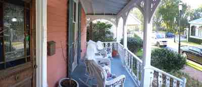 Pensacola:-Seville-Historic-District:-433-East-Zaragoza-Street_05.jpg:  leaded stained glass door, wicker furniture, victorian house, victorian front porch, gingerbread trim, historic village, shutters