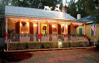 Pensacola:-Seville-Historic-District:-Lisa-Minshew-Attorney_04.jpg:  garland, bows, candy canes, american flag, holiday lights, wreath, shutters, tin roof, deer, fireplace, front porch, victorian cottage
