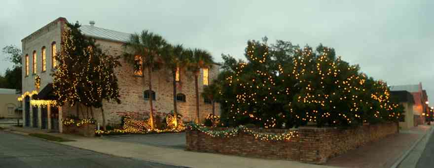 Pensacola:-Seville-Historic-District:-Michael-Mabire-Company_02.jpg:  christmas decorations, garland, bows, wreath, palm trees, awning, brick sidewalks, brick wall