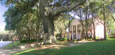 Scenic-Highway:-4450-Devereau-Drive_00.jpg:  colonial architectural style, white columns, shutters, crown molding pediment, circular driveway, carriage lamp, oak trees